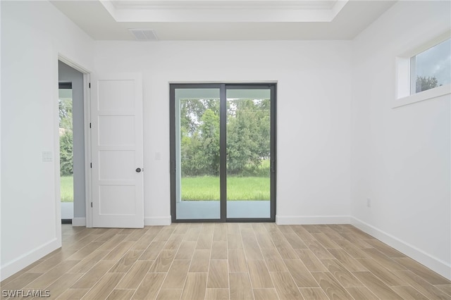 spare room with a tray ceiling and light hardwood / wood-style flooring