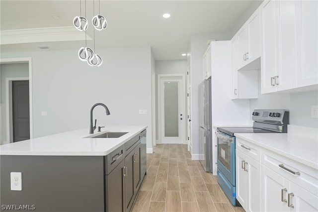 kitchen featuring appliances with stainless steel finishes, sink, pendant lighting, white cabinets, and an island with sink