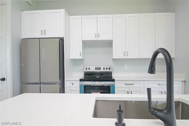 kitchen with light stone counters, sink, white cabinets, and stainless steel appliances