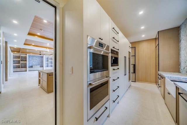 kitchen with modern cabinets, light stone countertops, double oven, white cabinetry, and recessed lighting