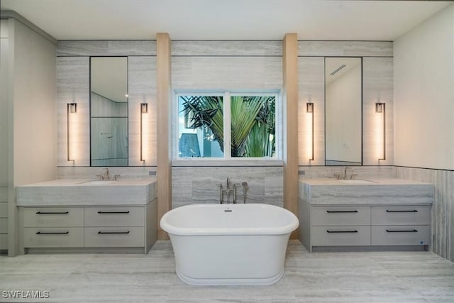 bathroom featuring a freestanding bath, two vanities, a sink, and tile walls