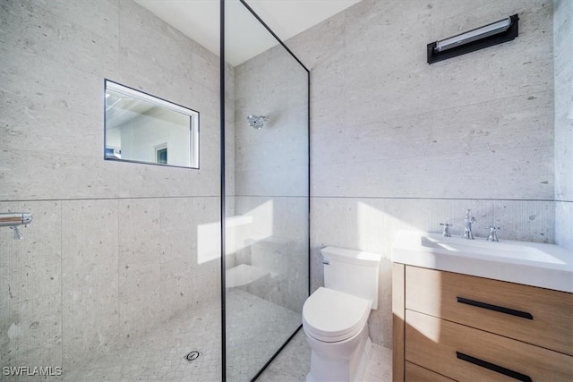 bathroom featuring toilet, tiled shower, and vanity