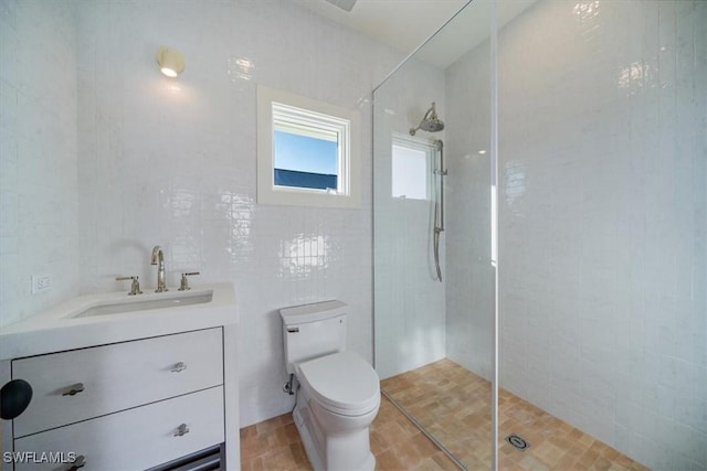bathroom featuring vanity, tile walls, walk in shower, and toilet