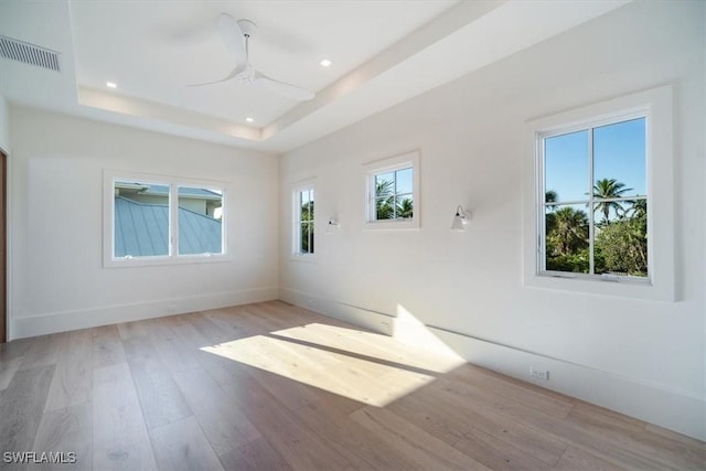 spare room with recessed lighting, visible vents, a tray ceiling, and light wood-style flooring