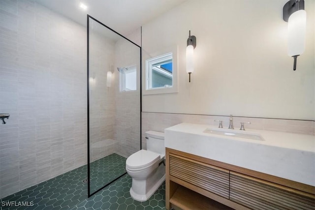 bathroom with toilet, tile walls, a walk in shower, vanity, and tile patterned flooring