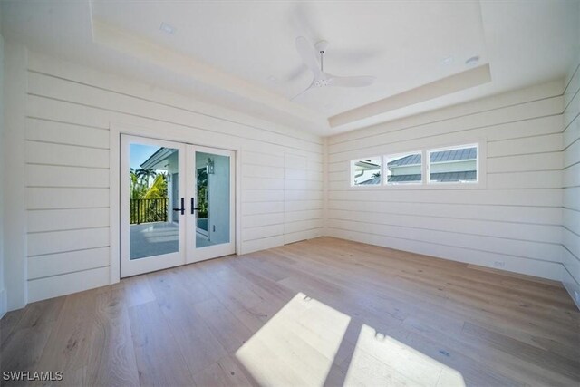 spare room with a wealth of natural light, french doors, wood finished floors, and a raised ceiling