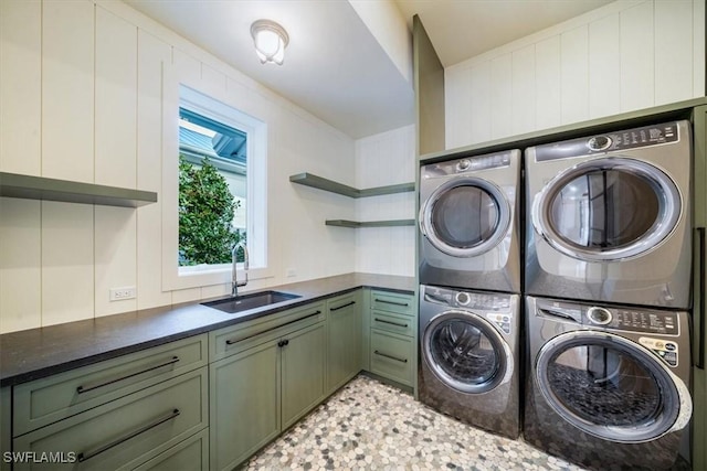 washroom featuring separate washer and dryer, a sink, cabinet space, and stacked washer / drying machine