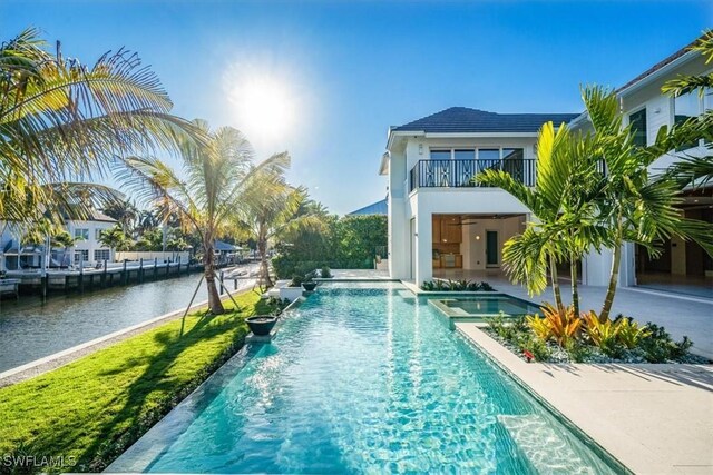 pool with a water view, a ceiling fan, and a patio area