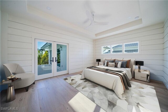 bedroom featuring a tray ceiling, access to exterior, and french doors
