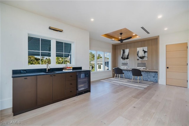 kitchen featuring dark countertops, visible vents, light wood finished floors, beverage cooler, and a sink