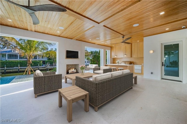 living area with wooden ceiling, a ceiling fan, a warm lit fireplace, and recessed lighting