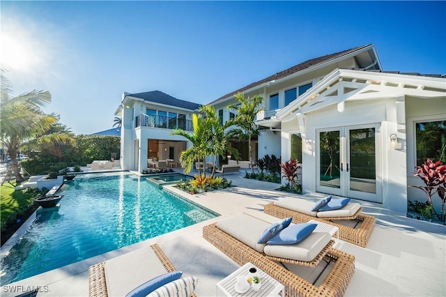 back of house featuring a patio, stucco siding, an outdoor pool, french doors, and a balcony