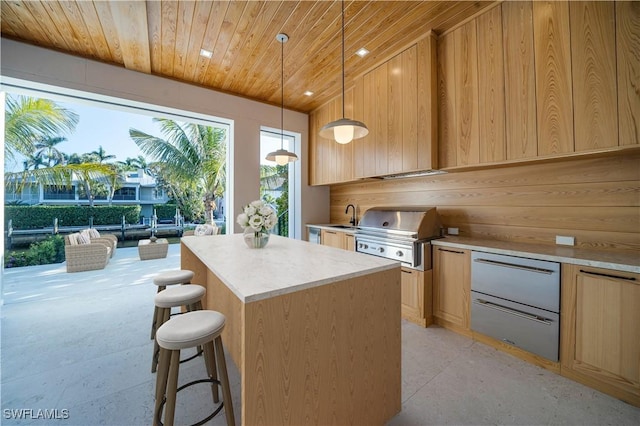 kitchen with a center island, wooden ceiling, a sink, light countertops, and light brown cabinetry