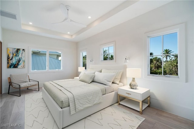 bedroom featuring visible vents, recessed lighting, a raised ceiling, and multiple windows