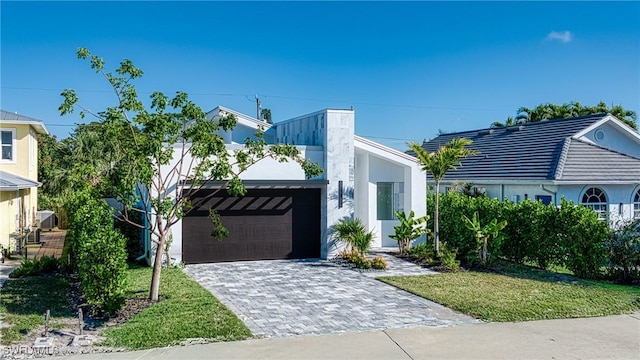 view of front of house featuring decorative driveway, a front lawn, and stucco siding