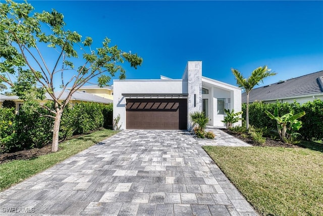 view of front of home with a garage, a front yard, decorative driveway, and stucco siding