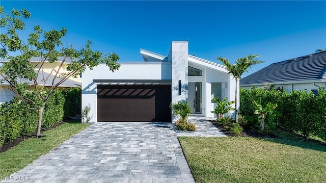 view of front facade with a front yard, decorative driveway, and stucco siding