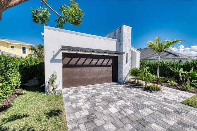 contemporary house with a garage, decorative driveway, and stucco siding