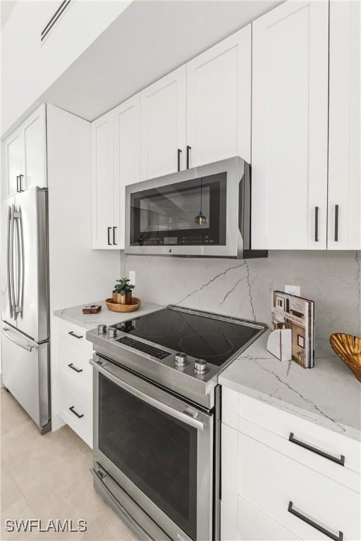 kitchen with light stone counters, appliances with stainless steel finishes, backsplash, and white cabinetry