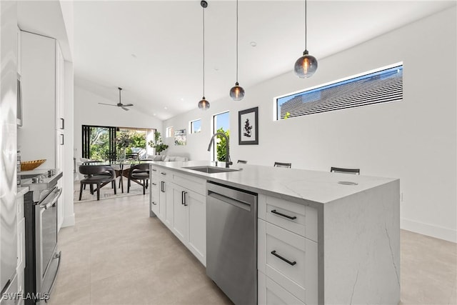 kitchen featuring light stone counters, appliances with stainless steel finishes, white cabinets, a sink, and an island with sink