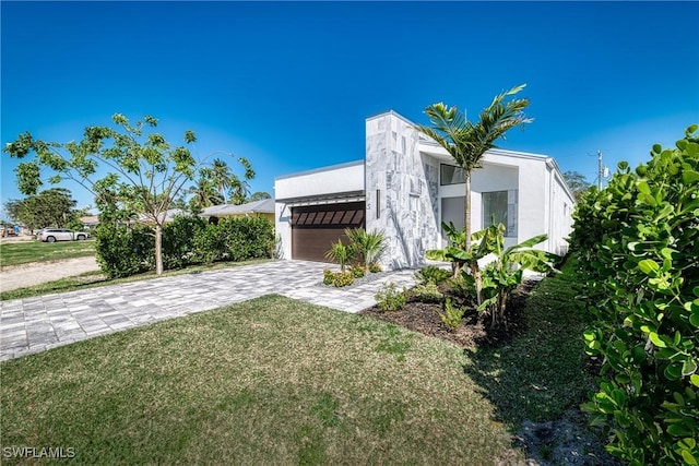 exterior space featuring a front yard, decorative driveway, an attached garage, and stucco siding