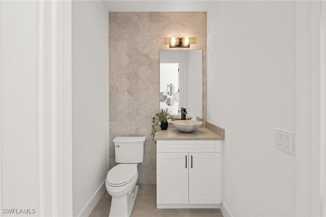 half bathroom featuring vanity, toilet, and baseboards