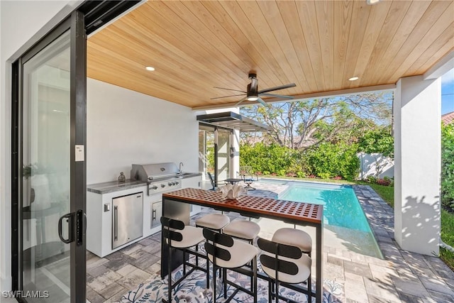 view of patio / terrace featuring exterior kitchen, a fenced in pool, ceiling fan, and area for grilling
