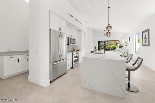 kitchen with open floor plan, stainless steel appliances, a sink, and white cabinetry