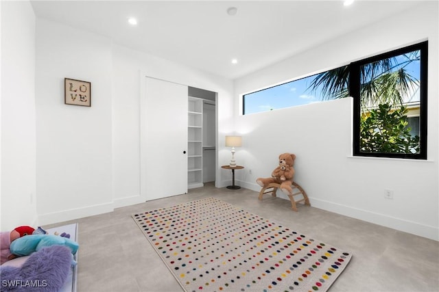living area featuring baseboards, concrete flooring, and recessed lighting