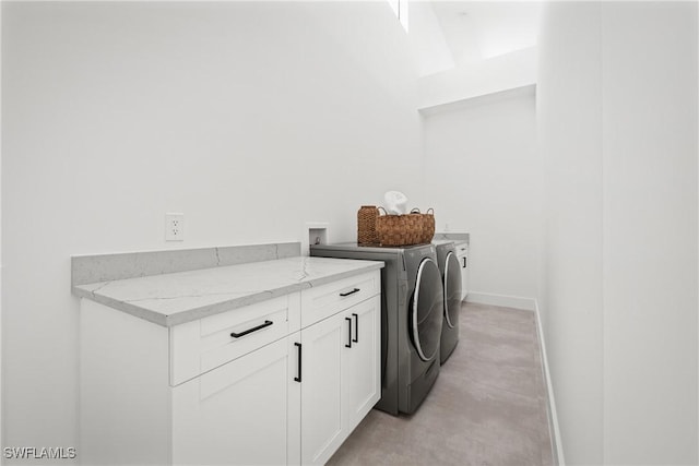 laundry room featuring baseboards, cabinet space, and washing machine and clothes dryer