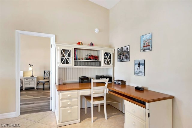 office with light tile floors and high vaulted ceiling