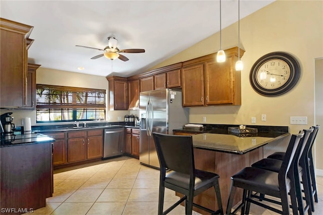 kitchen with decorative light fixtures, ceiling fan, appliances with stainless steel finishes, a breakfast bar, and light tile floors