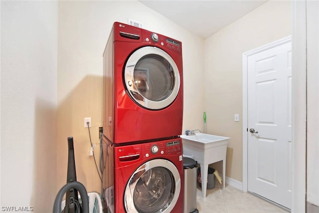 clothes washing area with stacked washer and clothes dryer and light tile flooring