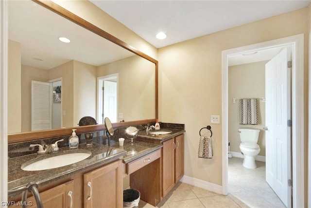 bathroom featuring double sink vanity, tile floors, and toilet