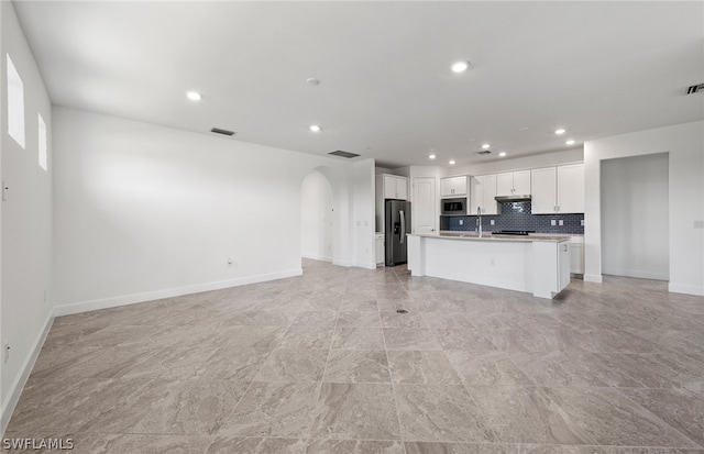 kitchen featuring a center island with sink, stainless steel appliances, white cabinets, tasteful backsplash, and light tile flooring