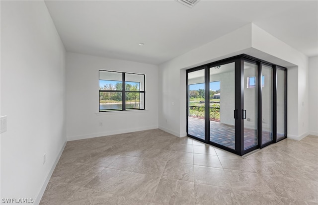 tiled empty room featuring french doors