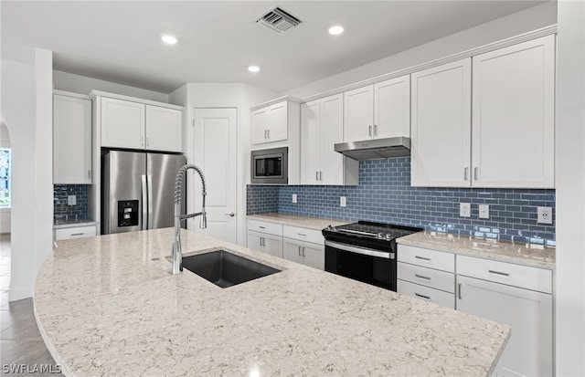 kitchen featuring an island with sink, stainless steel appliances, backsplash, sink, and white cabinets