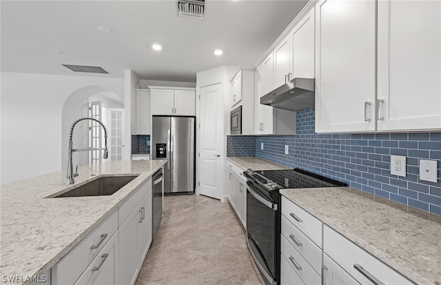 kitchen with stainless steel appliances, light tile flooring, backsplash, wall chimney exhaust hood, and white cabinetry