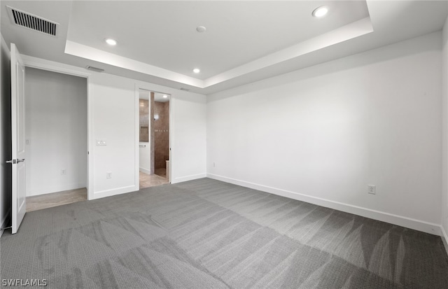 unfurnished bedroom featuring a raised ceiling, connected bathroom, and carpet floors