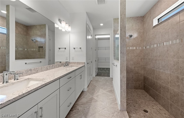 bathroom featuring a tile shower, dual sinks, tile flooring, and large vanity