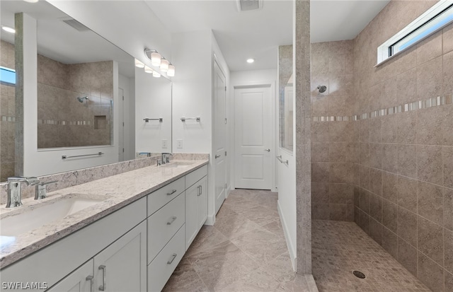 bathroom with tiled shower, tile flooring, and dual bowl vanity