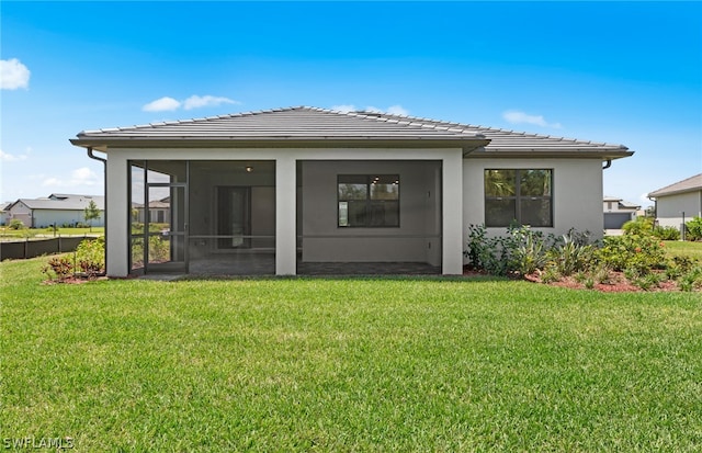 rear view of property featuring a sunroom and a lawn