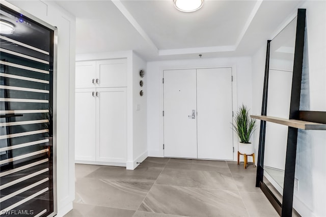 tiled entrance foyer with a tray ceiling and beverage cooler