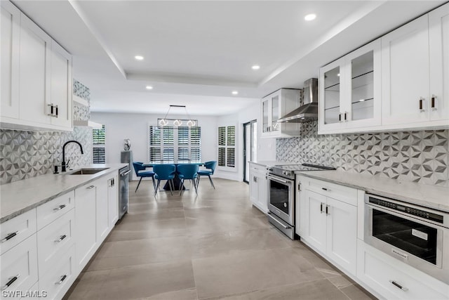 kitchen featuring wall chimney exhaust hood, tasteful backsplash, a healthy amount of sunlight, and appliances with stainless steel finishes