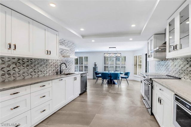 kitchen featuring appliances with stainless steel finishes, backsplash, a tray ceiling, and sink