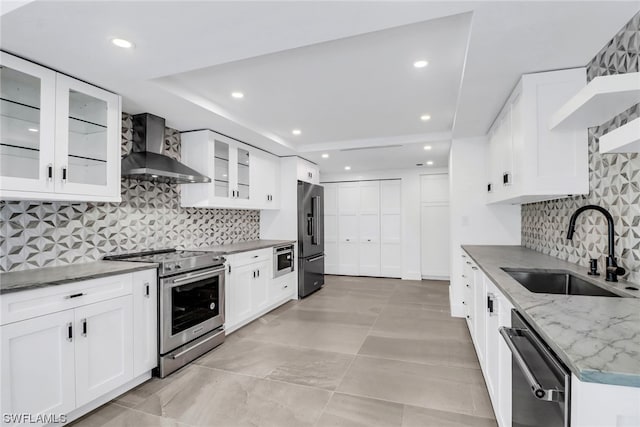 kitchen featuring white cabinetry, backsplash, sink, stainless steel appliances, and wall chimney exhaust hood