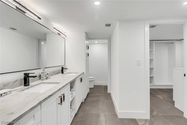 bathroom with double sink vanity, toilet, and tile floors