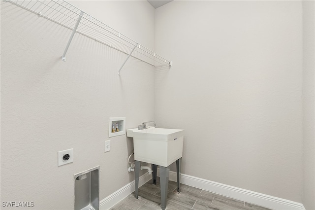 clothes washing area with electric dryer hookup, hookup for a washing machine, and light hardwood / wood-style floors