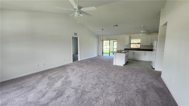 unfurnished living room featuring carpet, ceiling fan, high vaulted ceiling, and sink