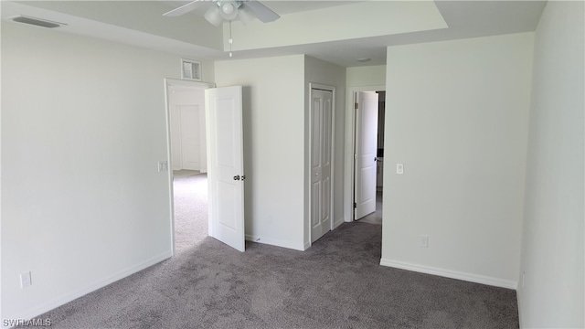 spare room with ceiling fan and dark colored carpet